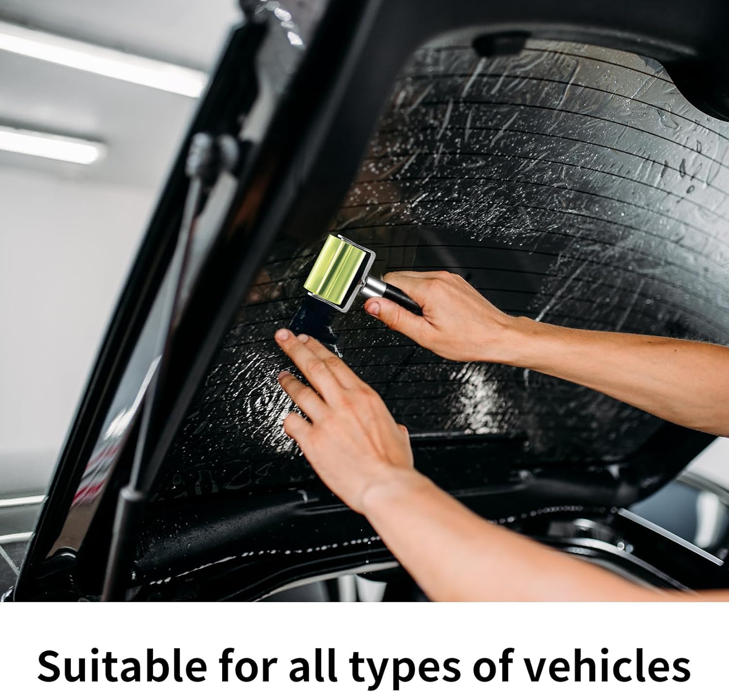 Person cleaning a car window with a squeegee in a garage setting