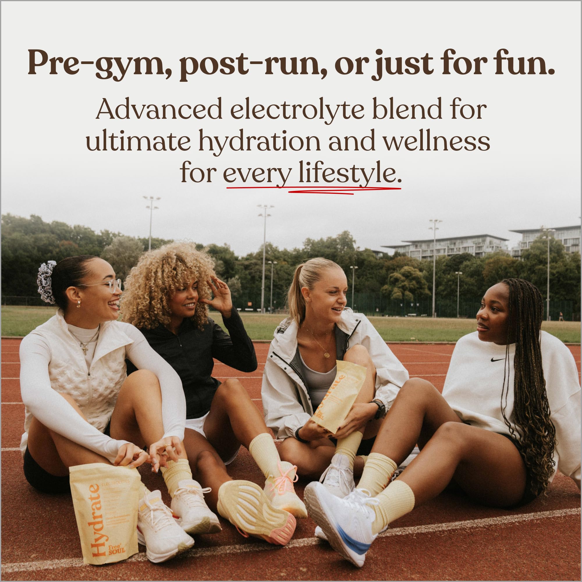 Four women sitting on a track with sports drinks, promoting an advanced electrolyte blend for hydration.