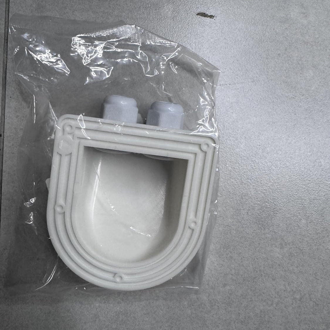 White plastic component in clear packaging on a gray surface