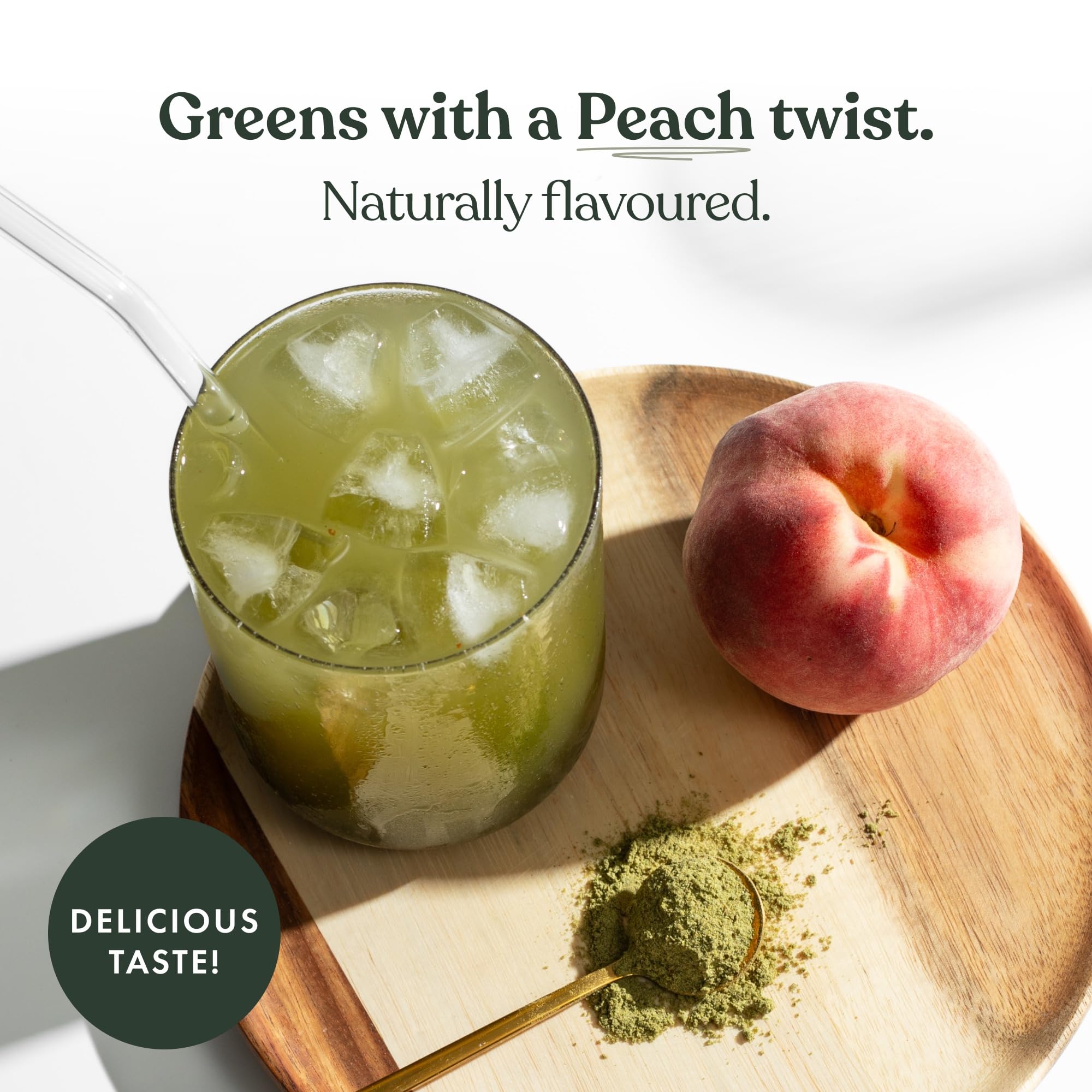 Green drink with ice and a peach on a wooden board, with text 'Greens with a Peach twist.'