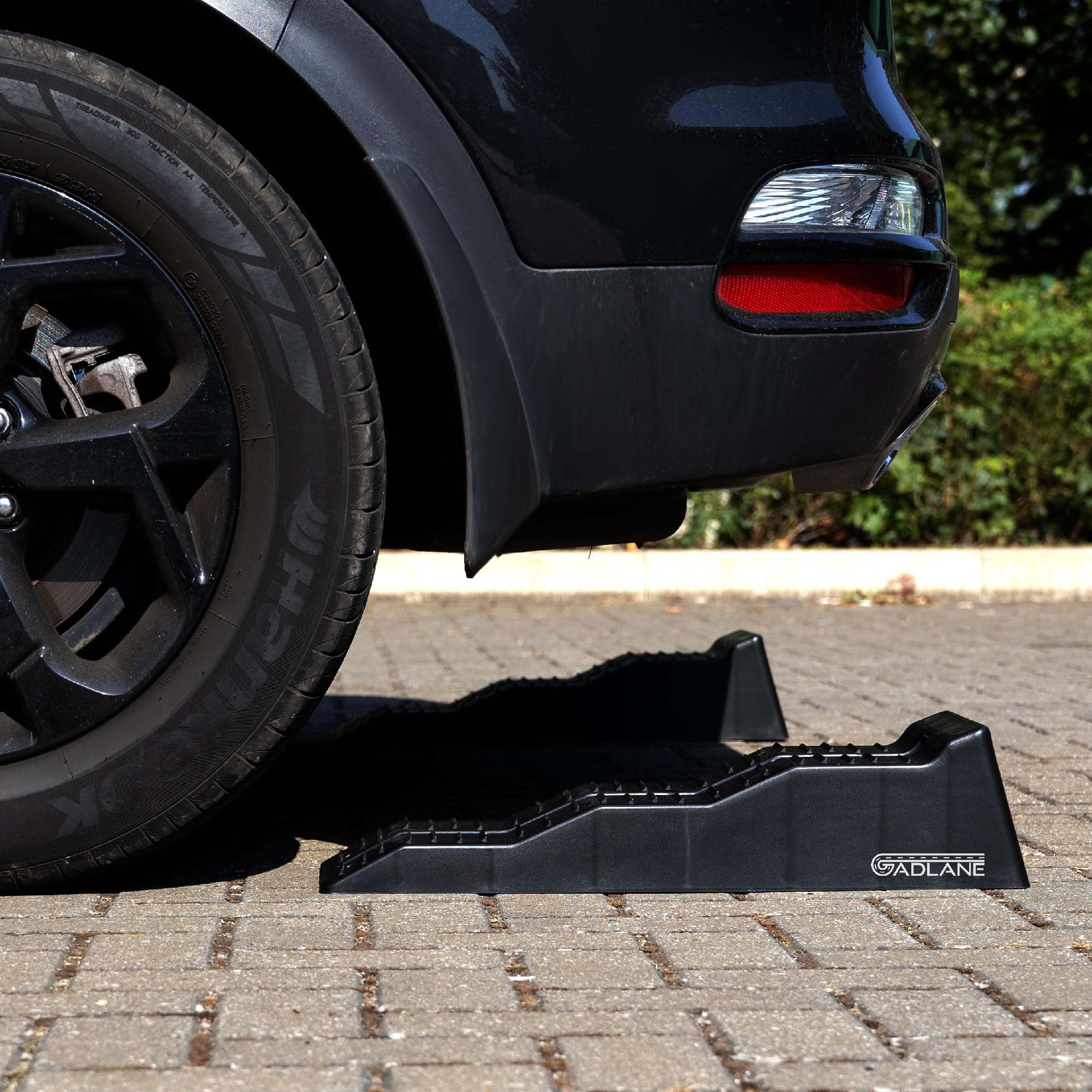 Car using a black car ramp on a paved surface