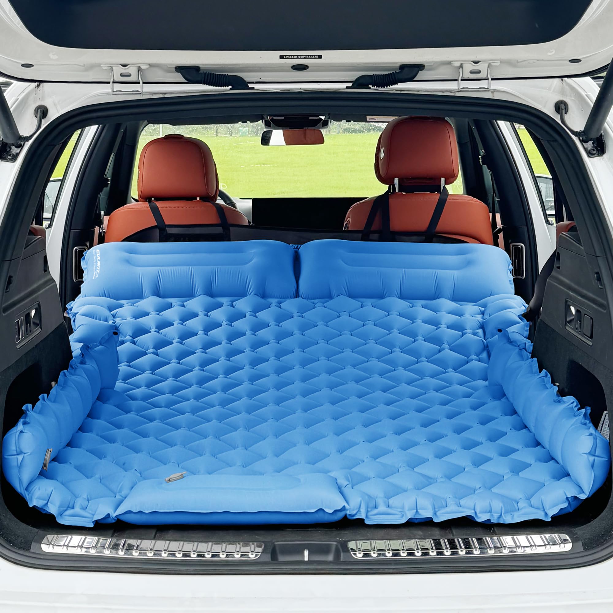 Blue inflatable mattress in the back of a car with brown leather seats.