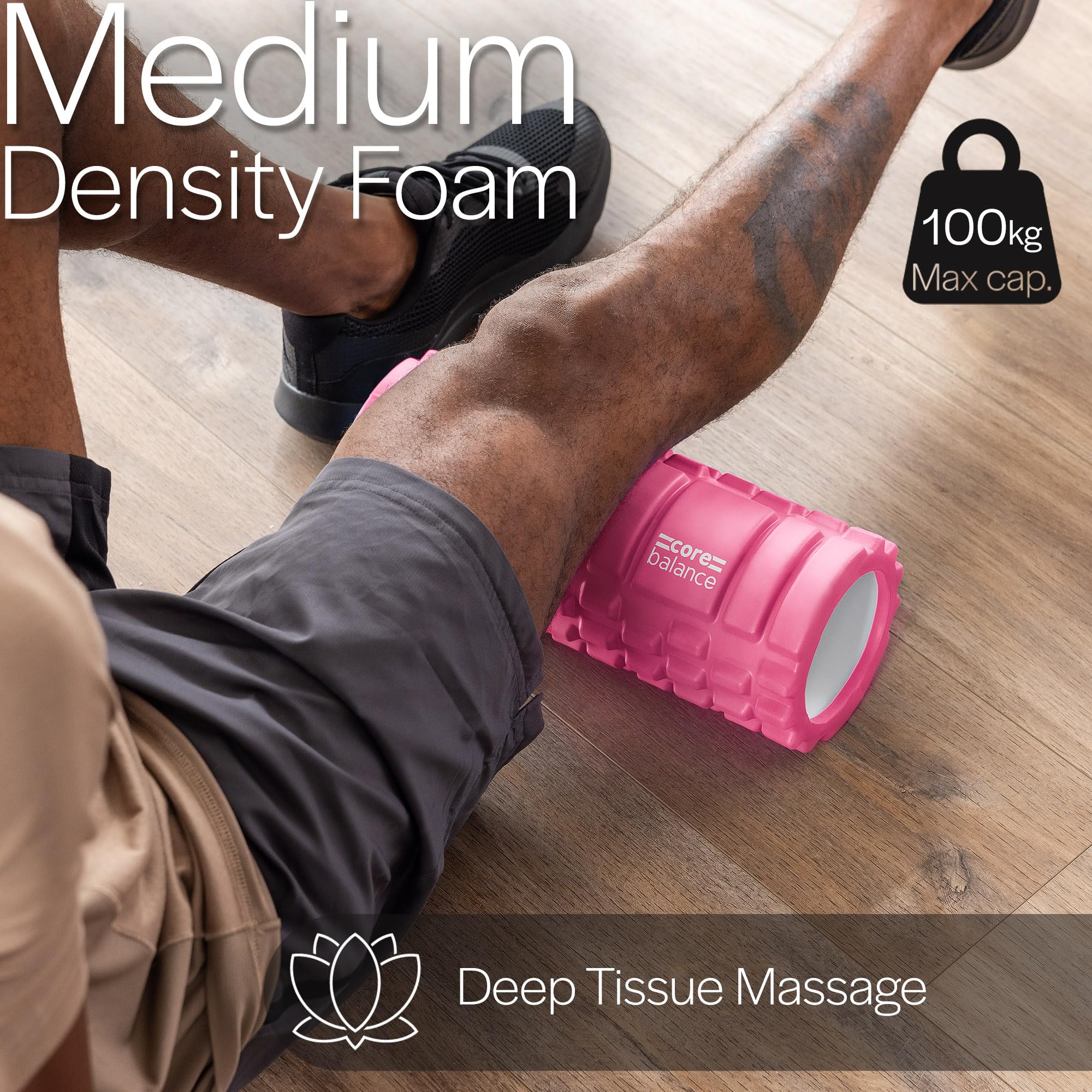 Person using a pink foam roller for deep tissue massage on a wooden floor.