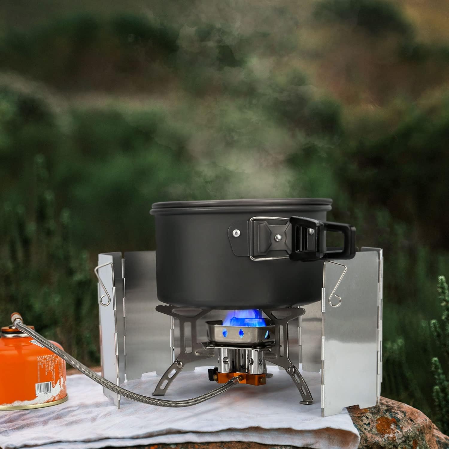 Portable camping stove with a pot on a blurred natural background